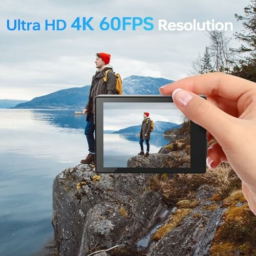 Person standing on a cliff by a lake with a camera screen showing 4K 60FPS resolution.