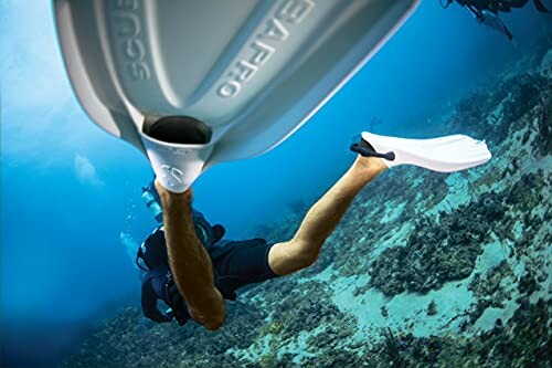 Diver underwater wearing white fins swimming near coral